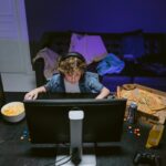 A young boy plays video games at home, surrounded by snacks, showcasing the gaming lifestyle.