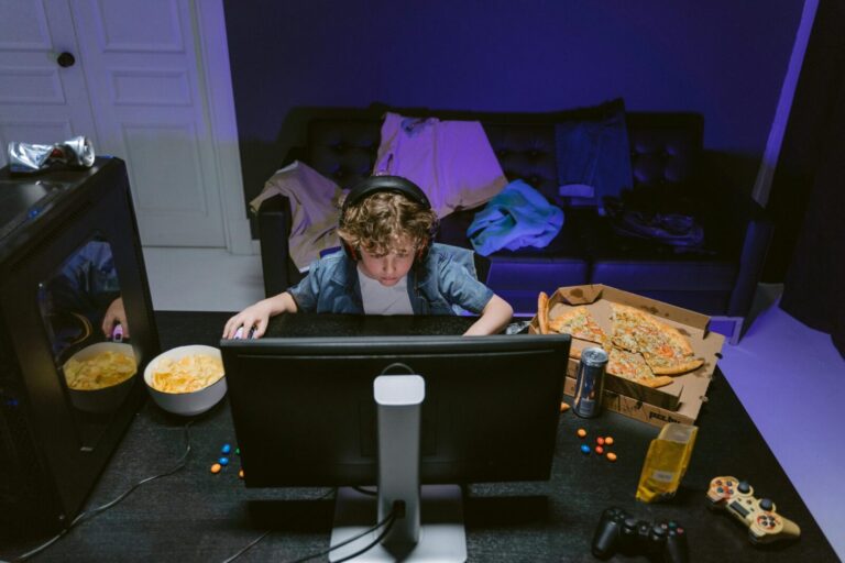 A young boy plays video games at home, surrounded by snacks, showcasing the gaming lifestyle.