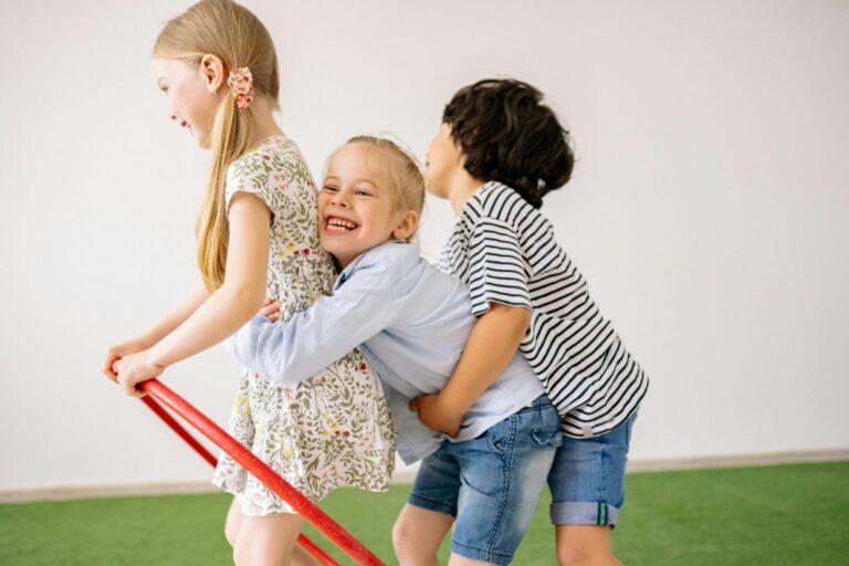 Three children joyfully play indoors with a hula hoop, showcasing happiness and togetherness.