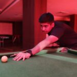 A man leaning over a pool table with a ball in his hand