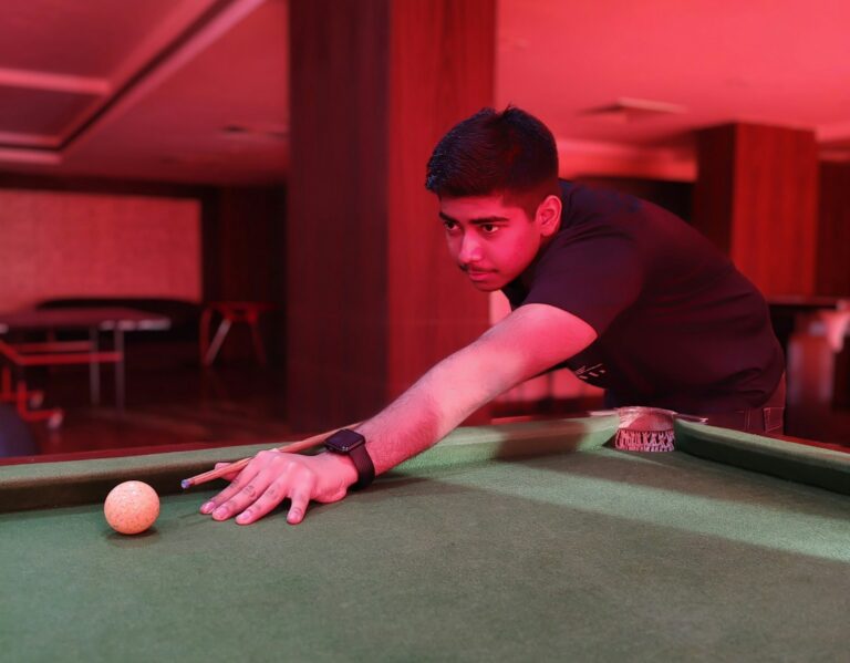 A man leaning over a pool table with a ball in his hand